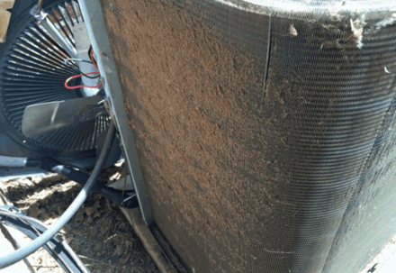 Dirty outdoor air conditioner coil and fan with wiring visible.