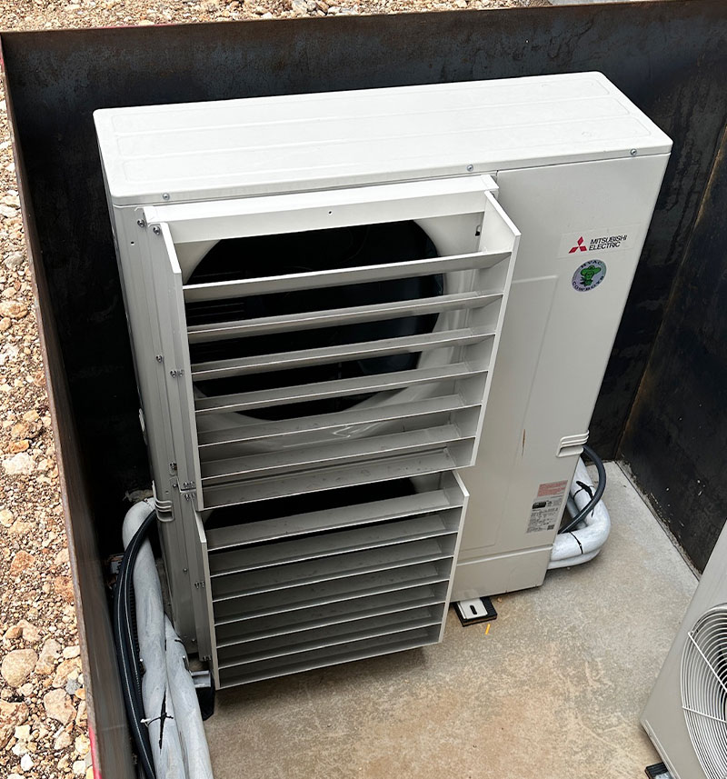 Mitsubishi electric outdoor unit with protective grille on concrete platform.