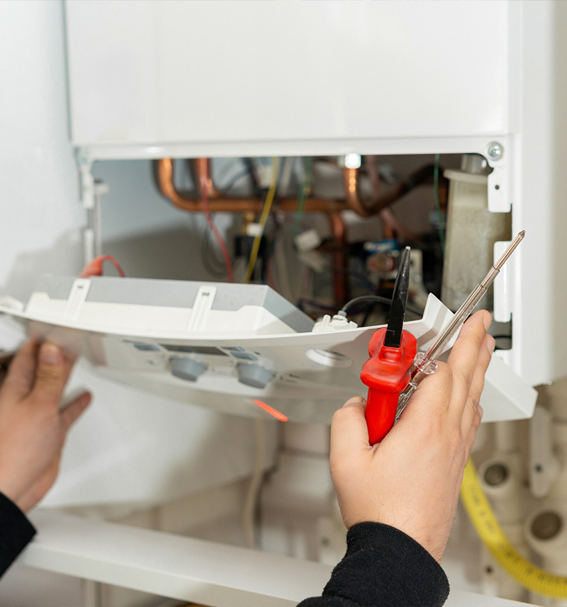 Person fixing a boiler with tools, performing maintenance work.