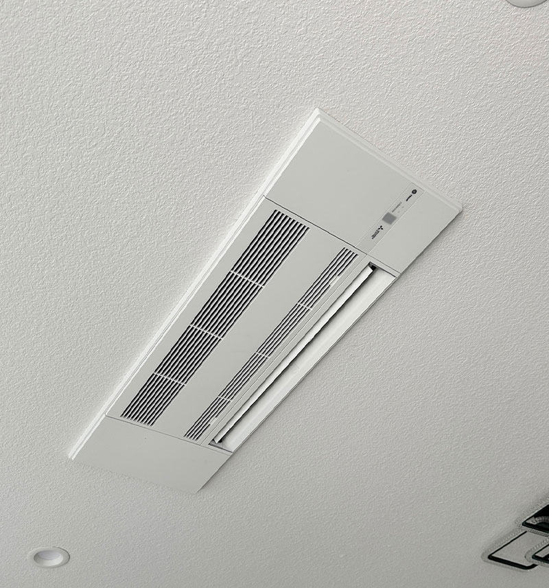 Ceiling-mounted air conditioner unit with vent and control panel.