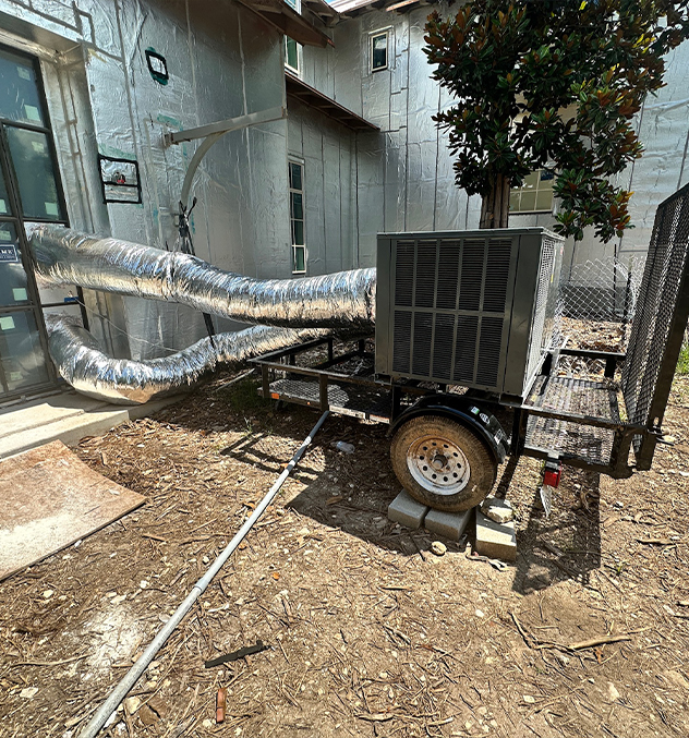 Portable air conditioning unit with ducts connected to a building exterior for cooling.