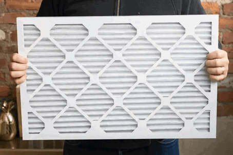 A person holding a large rectangular air filter with a honeycomb pattern